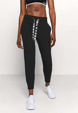 Svarta joggerbyxor i mjukt material, med avslappnad passform, elastisk midja, två sidofickor och tryckta snörningsdetaljer.