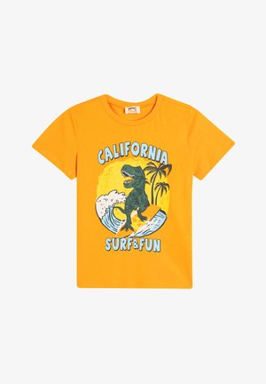 Lyhythihainen oranssi t-paita, jossa on vihreä dinosaurus surffaamassa palmujen ja aaltojen taustalla. Paidassa on painettu teksti "CALIFORNIA SURF & FUN."
