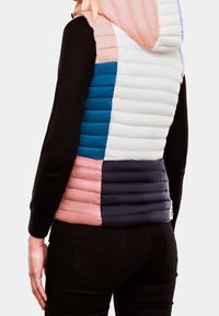 Gepolsterte Weste mit einer Mischung aus Pastellfarben: pink, blau, weiß und navy. Verfügt über eine Kapuze und gesteppten Stoff. Schwarzes Oberteil darunter.