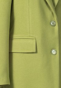 Green wool-blend coat featuring smooth texture, notch lapel, a single pocket, and two round buttons with matching color.