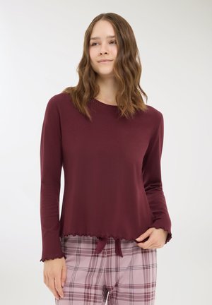 Top bordeaux a maniche lunghe con scollatura rotonda, orlo ondulato e un fiocco in vita, abbinato a pantaloni da pigiama a quadri rosa chiaro.