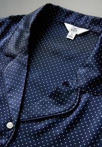 Navy spalvotas palaidinė su satino apdaila, įpjovimu ant kaklo ir sagomis, su mažomis baltomis taškelėmis tolygiai išdėstytomis audinyje.