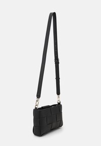 Czarna pleciona skórzana torba na ramię o fakturowanej powierzchni, prostokątnym kształcie, regulowanym pasku i srebrnych metalowych akcentach.