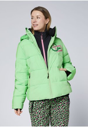 Light green puffer jacket with a black inner lining, pink zipper, and logo. Worn with multi-colored leopard print pants.