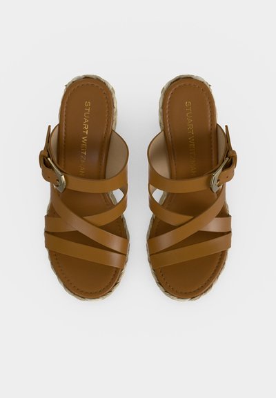 Paire de sandales en cuir marron à enfiler avec des brides croisées et des boucles latérales réglables sur des semelles tressées.