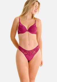 Magenta lingerie set met een gladde, gevoerde bh met kantaccenten en een bijpassende string met een bloemenkant tailleband.