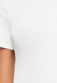 Άσπρο ριμπ μπλουζάκι με κοντά μανίκια, διαθέτει υφασμάτινη υφή και εφαρμοστή σχεδίαση που τονίζει τις καμπύλες.
