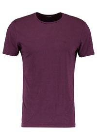 Camiseta de manga corta y cuello redondo en púrpura profundo, fabricada en algodón suave, con un detalle del logo en el pecho y una textura suave.