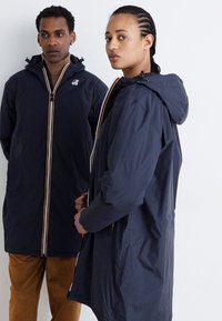 Vestes légères bleu marine avec capuche, dotées de rayures verticales contrastantes sur les zips et d'une coupe décontractée. Texture lisse et manches longues.