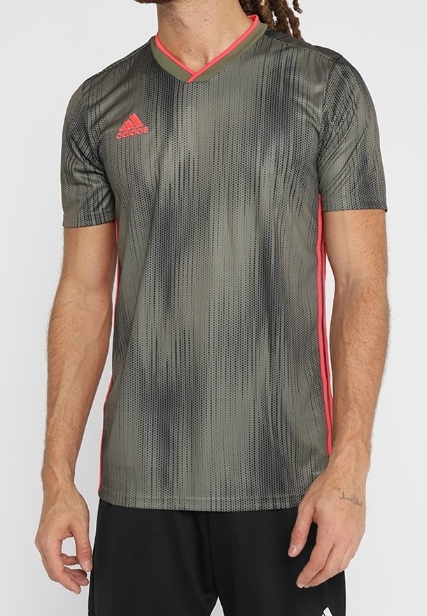 Kortärmad grå träningsskjorta med svart prickigt mönster, rosa detaljer och v-ringad design. Tillverkad av lätt, andningsbart material.