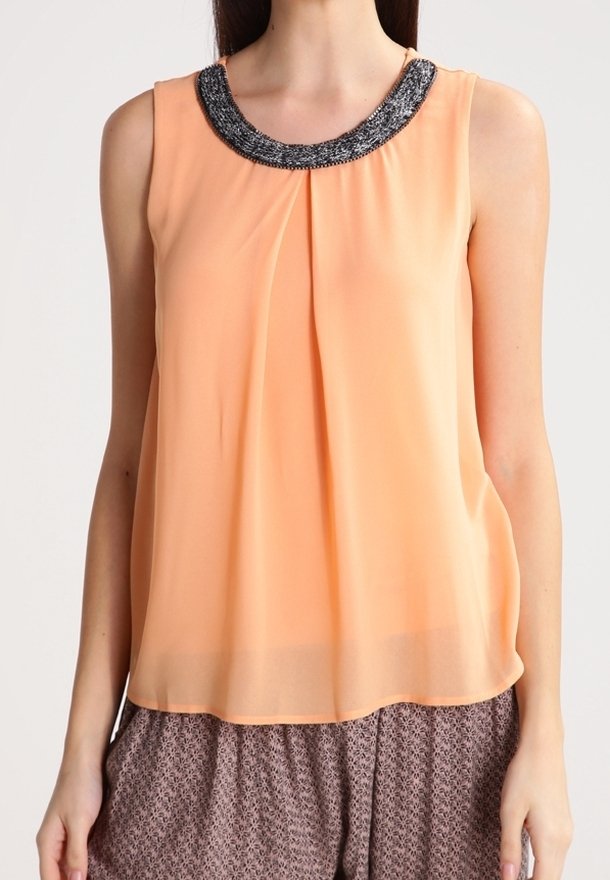 Persikofärgad ärmlös blus med en pärlad svart och silver halsringning, som har en flödande silhuett och ett mjukt, lättviktigt tyg.