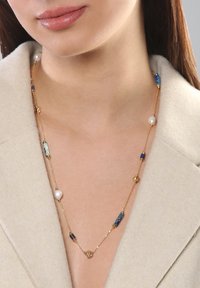 Goldene Halskette mit gemischten Perlen, darunter weiße Perlen und blaue Steine, mit einer zarten Kette und unterschiedlich geformten Akzenten.