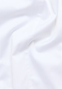 Tessuto bianco con una texture liscia, che presenta lievi pieghe e dettagli di cucitura, trasmettendo un aspetto leggero e morbido.