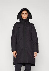 Parka nera impermeabile con colletto alto e cappuccio regolabile. Presenta bottoni a pressione, due tasche laterali e una vestibilità comoda. Texture liscia.
