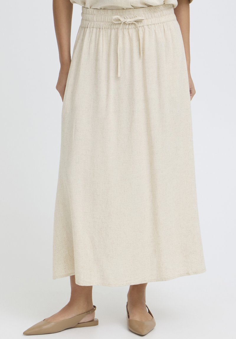 Jupe beige longueur cheville avec taille élastique et cordon de serrage, portée avec des ballerines beige à brides arrière pointues.