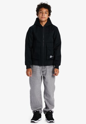 Musta vetoketjullinen huppari, jossa on huppu, kaksi etutaskua ja ribattu hihansuu, yhdistetty harmaisiin farkkuihin ja mustiin urheilukenkisiin.