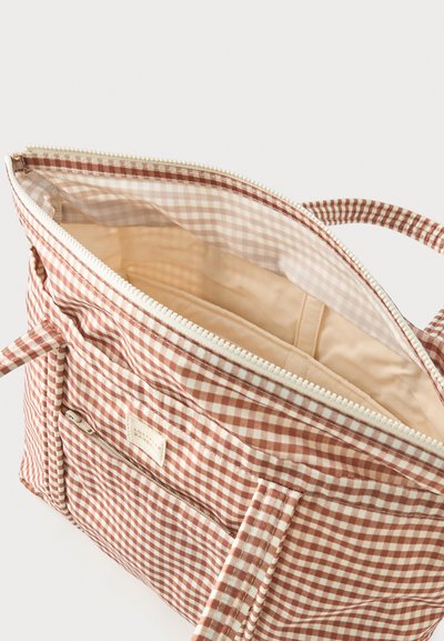 Καφέ και λευκή τσάντα tote με κλείσιμο με φερμουάρ, εξωτερική τσέπη με φερμουάρ, υφασμάτινες λαβές και μπεζ εσωτερική επένδυση με μικρές τσέπες.