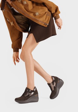 Bottines en nubuck marron avec une semelle compensée, présentant des accents métalliques et un mélange de textures. Lacets et un logo subtil sur le côté.