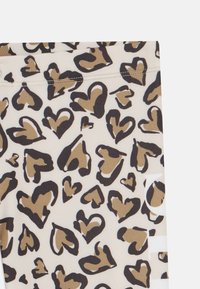 Beige szövetből készült leggings, barna és fekete szívmintával. Sima textúra és elasztikus derékpánt a kényelem érdekében.