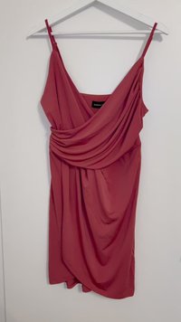 Rotes ärmelloses Kleid mit drapiertem Vorderteil, aus weichem Stoff gefertigt. Verfügt über dünne Träger und eine lockere Passform, die bis zur Mitte des Oberschenkels reicht.