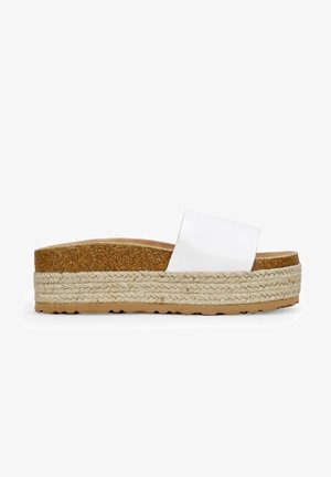 White flat slide sandal with a wide strap, cork footbed, and woven jute midsole. Features a textured rubber sole for grip.