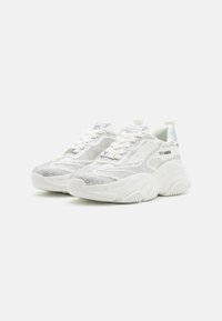 Weiße Sneakers mit einer glänzenden silbernen Textur, Schnürdesign, dicke Sohle und Markendetail an der Seite.