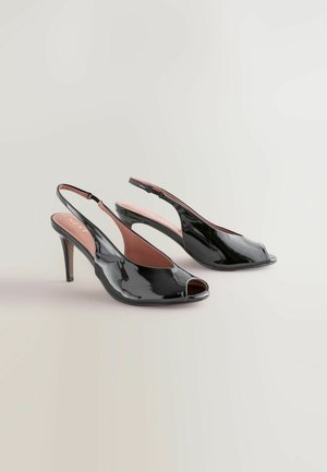 Czarne, lakierowane zamszowe sandały na obcasie z odkrytymi palcami i smukłym, średniej wysokości obcasem typu stiletto, prezentowane na jasnym tle.
