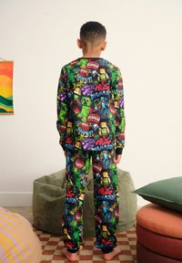 Green pajama set featuring Minecraft characters and graphics. Long sleeves, elastic waistband, multi-colored patterns. Soft fabric texture.