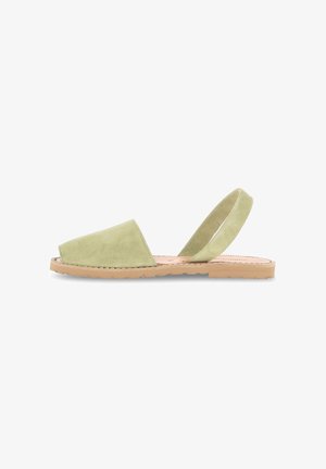 Sandale à talon bas en daim vert, à enfiler, avec un bout ouvert et une sangle élastique autour de la cheville. Dispose d'une semelle de couleur naturelle. Design simple et plat.