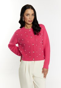 Cardigan lavorato a maglia di un vivace rosa con decorazioni in perle tonde, scollo a girocollo e chiusura con bottoni. Design aderente con dettagli a coste.