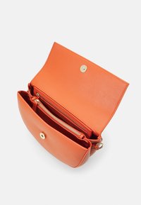 Oranžová kožená crossbody kabelka s klopou, vybavená zlatým zacvakávacím knoflíkem, vnitřní zipovou kapsou a hladkým povrchem. Otevřený pohled.