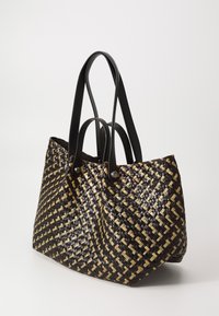 Vevd handlenett i svart og beige, med et geometrisk mønster. Svart skinnhåndtak med metallakenter, robust rektangulær form.