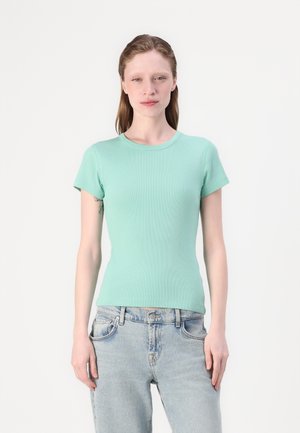 Mintgrønn ribbet kortermet t-skjorte med en tettsittende design, rund hals og myk tekstur, kombinert med lyseblå denimjeans.