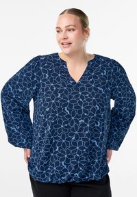 Navy blouse with light blue floral pattern, V-neckline, and long sleeves. Features gathered bottom hem and soft, textured fabric.
