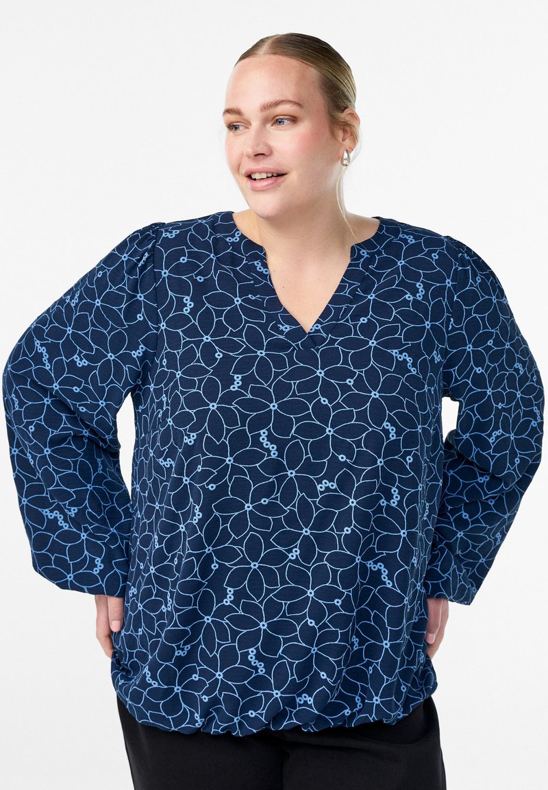 Navy blouse with light blue floral pattern, V-neckline, and long sleeves. Features gathered bottom hem and soft, textured fabric.