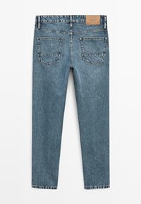 Blauwe spijkerbroek plat neergelegd, achterkant zichtbaar met twee achterzakken en een bruin lederen merklabel op de tailleband.