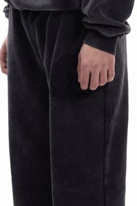 Ciemnoszare spodnie dresowe wykonane z miękkiej tkaniny, z wytłaczanym logo na dolnej części nogawki, z elastycznym pasem i mankietami.