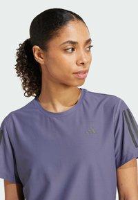 Lila feuchtigkeitsableitendes Sport-T-Shirt mit kurzen Ärmeln, Rundhalsausschnitt und drei schwarzen Akzentstreifen auf den Schultern.