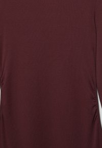 Top bordeaux a maniche lunghe realizzato in tessuto morbido, con cuciture laterali arricciate e una texture liscia. Design semplice e aderente.