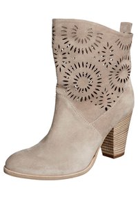 Beżowy zamszowy botek za kostkę z wyciętym kwiatowym wzorem i 3-calowym, warstwowym obcasem. Zaokrąglony nosek i gładka faktura podkreślają ogólny wygląd.