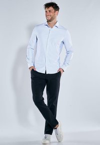 Gestreiftes blau-weißes Hemd, zugeknöpft, mit langen Ärmeln. Kombiniert mit dunklen Hosen und weißen Sneakers. Glattes Gewebe, maßgeschneiderte Passform.