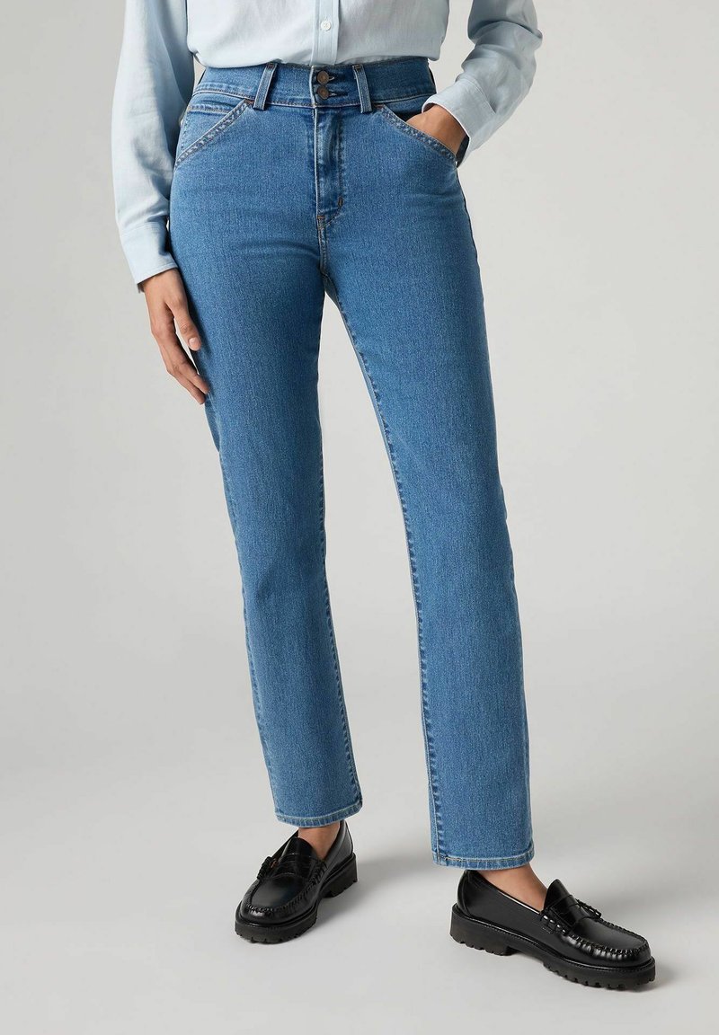 Jeans blu a vita alta con un taglio dritto, realizzati in denim, con chiusura a bottone e tasche frontali, abbinati a mocassini neri.