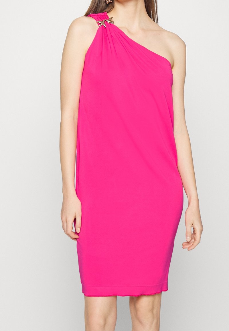 Fuksjowa sukienka na jedno ramię wykonana z miękkiego materiału, z podwieszanym krojem i dekoracyjnymi metalowymi akcentami na ramieniu.