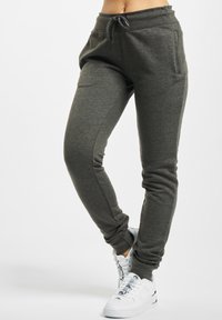 Jogging gris foncé en tissu doux, avec une taille élastique à cordon, des poches latérales, une coupe slim et des poignets en ribbed.