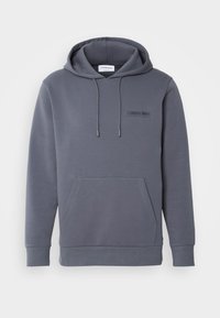 Siv hoodie s kapuco s kengurujem žepom, kapuco na vezanje in subtilnim logotipom blagovne znamke spredaj. Gladka tekstura tkanine.