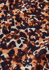 Tissu à imprimé léopard abstrait marron, noir et beige avec une texture côtelée et des formes arrondies irrégulières.