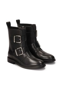 Botas de cuero negro hasta el tobillo con dos correas anchas y hebillas cuadradas de plata, suelas planas y una textura suave. Cierre de cremallera en la parte posterior.