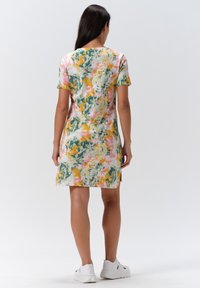 Kortärmad klänning med färgglad abstrakt mönstring som innehåller nyanser av rosa, grönt och gult. Tillverkad av mjukt tyg med en avslappnad passform och sidssssprund.