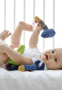 Soft toy set with bright colors including green, blue, and yellow. Features various shapes and textures, including stripes and plush fabrics.
