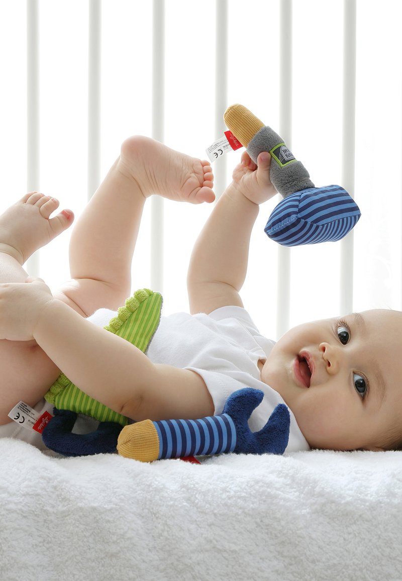 Soft toy set with bright colors including green, blue, and yellow. Features various shapes and textures, including stripes and plush fabrics.